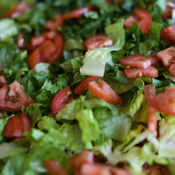 Close-up of a fresh salad with crisp green lettuce and sliced red tomatoes.
