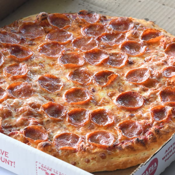 A close-up of a hot, cheesy pepperoni pizza from Louie's Pizza in a cardboard box.