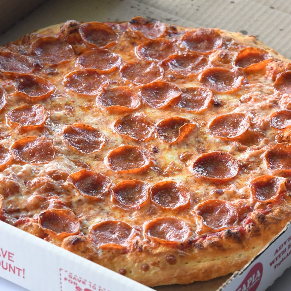A close-up of a hot, cheesy pepperoni pizza from Louie's Pizza in a cardboard box.